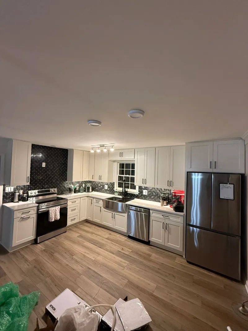 Renovated kitchen with white shaker cabinets, oversized stainless farmhouse sink, and black-and-white penny-tile backsplash.