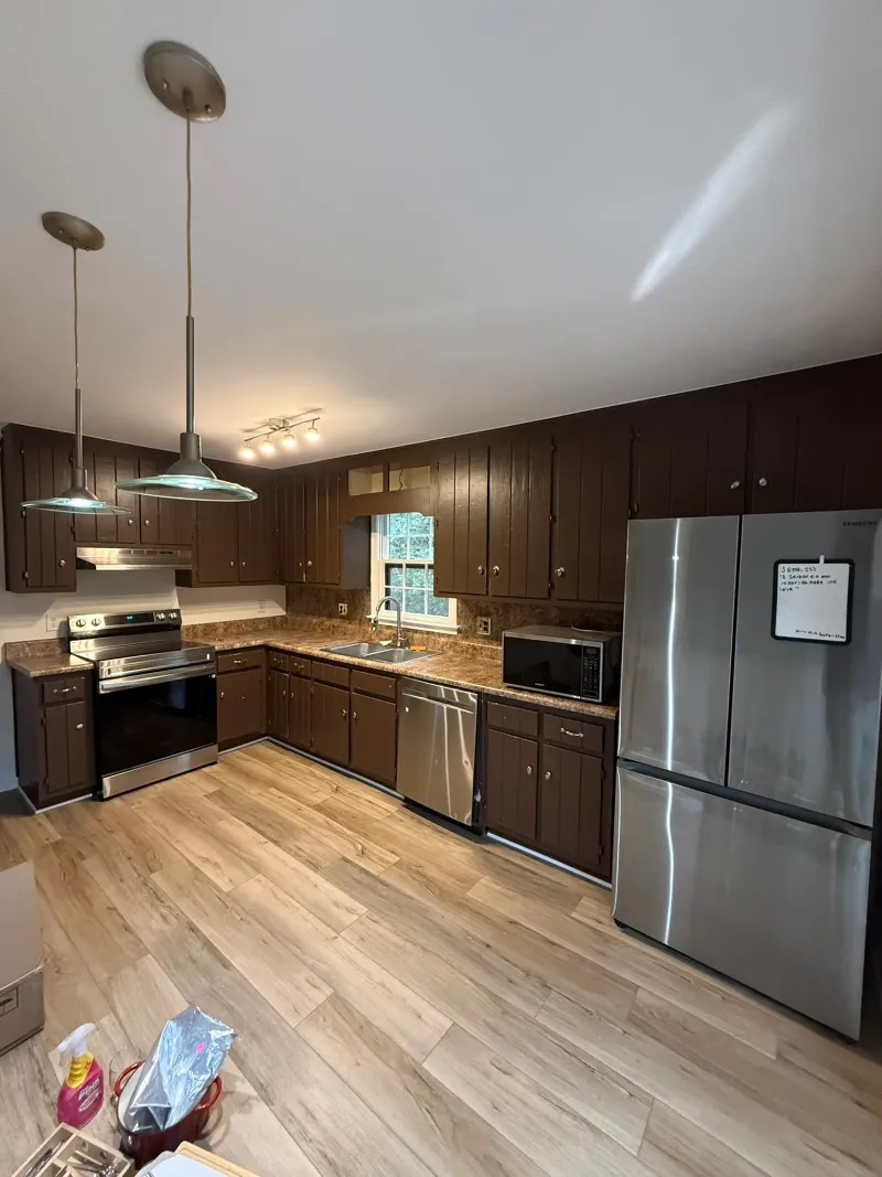 Dated kitchen with heavy dark cherry cabinets, brown granite countertops, and stainless appliances.